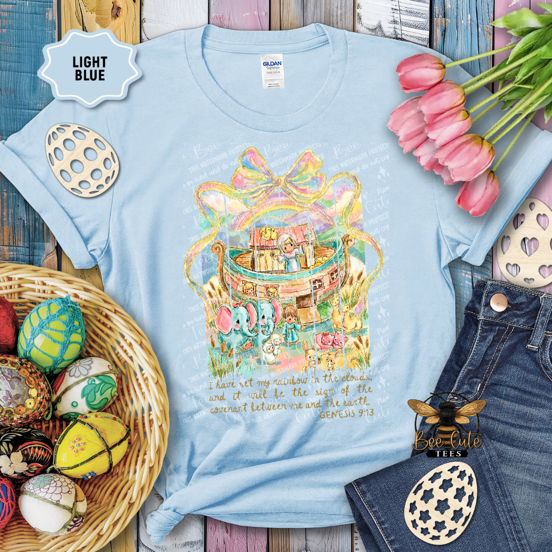 Light blue t-shirt with colorful graphic design on a wooden surface with decorative items.