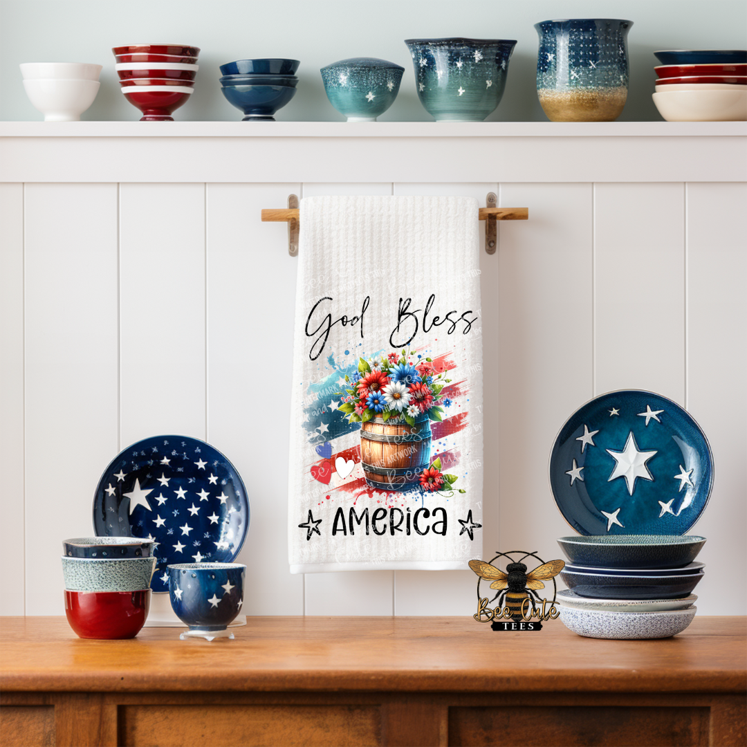 Decorative kitchen set with 'Good Bless America' towel, plates, and bowls on a wooden shelf.