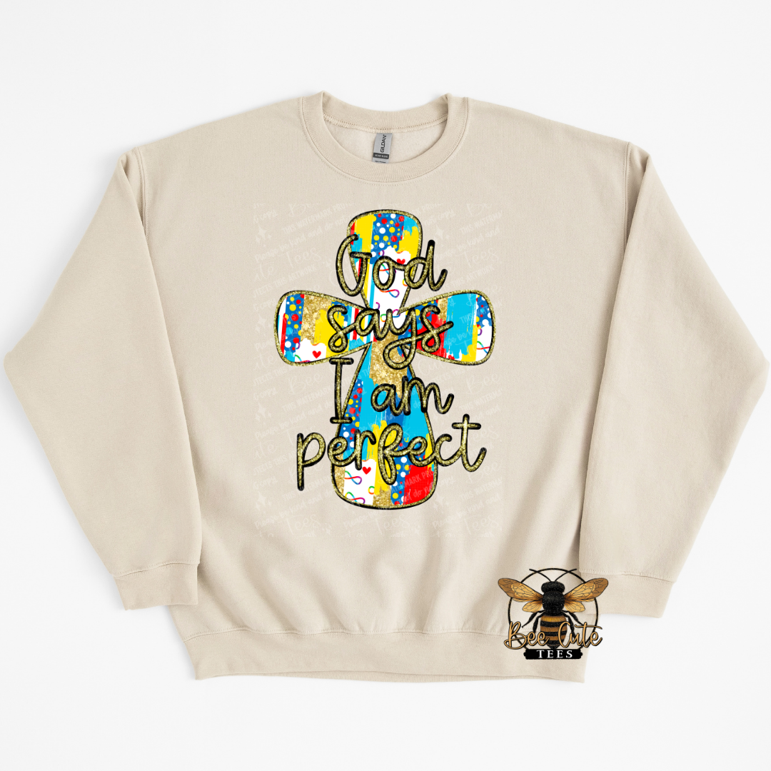 Beige sweatshirt with a colorful cross design and 'God says I am perfect' text on a white background.