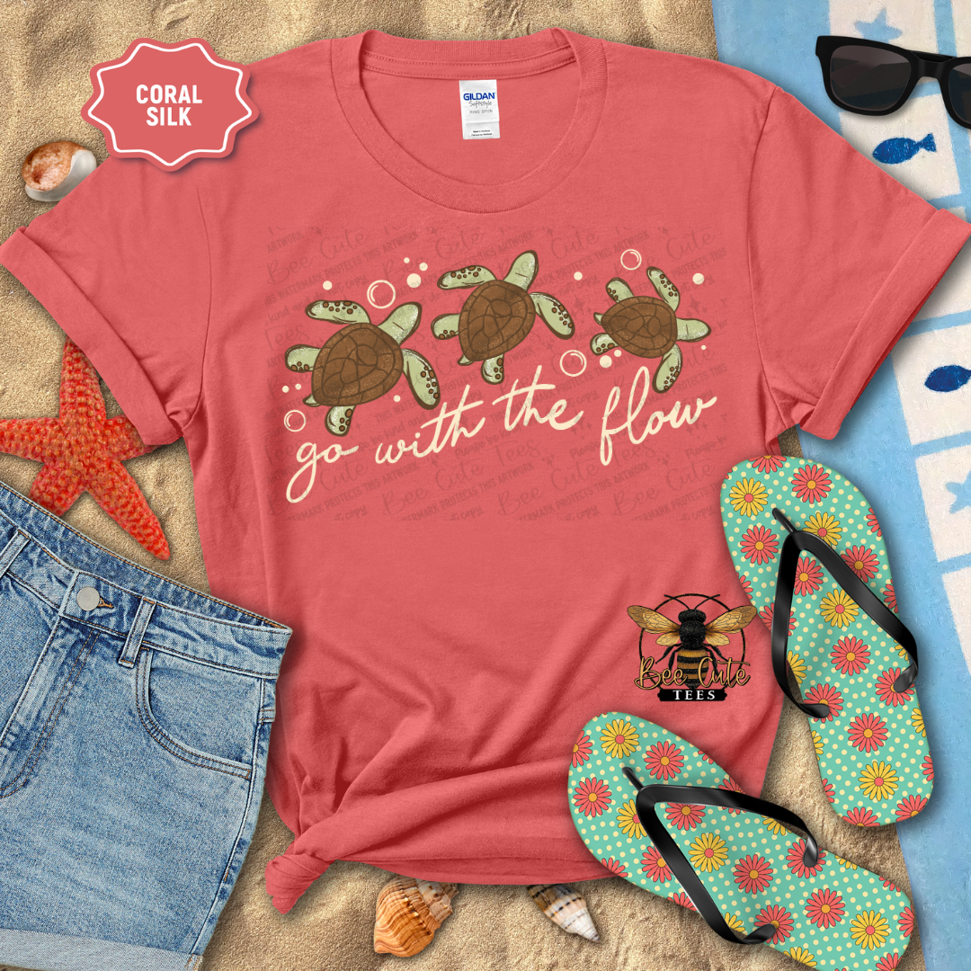 Red t-shirt with turtle design and 'go with the flow' text, surrounded by beach accessories.