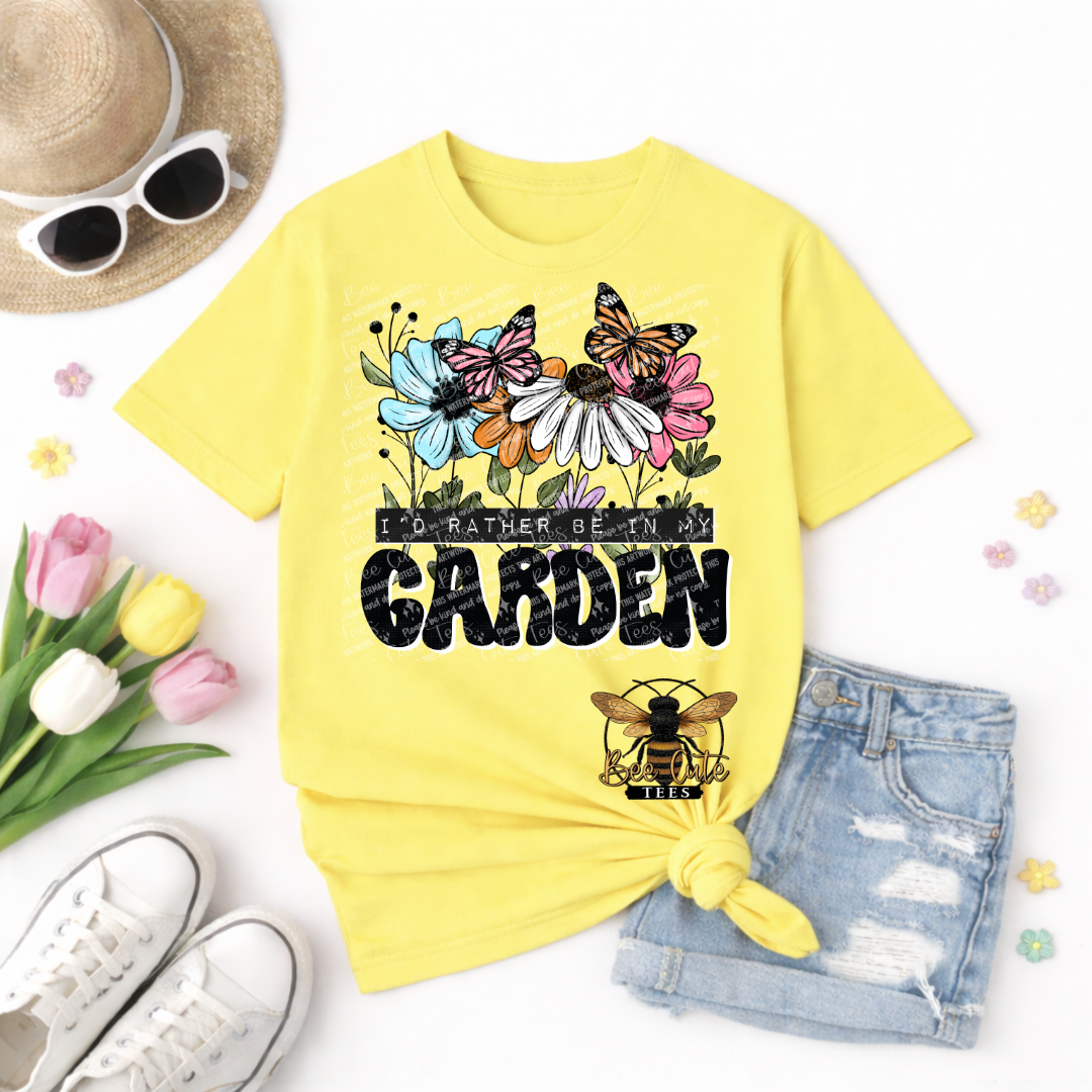 Yellow t-shirt with floral design and text 'I'd rather be in my garden' on a white background with accessories.