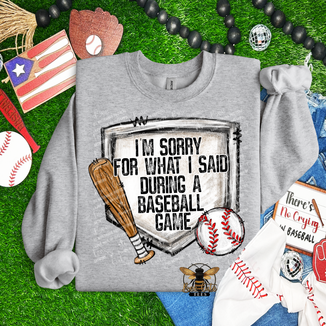 Gray sweatshirt with baseball-themed design on grass with sports-themed accessories.