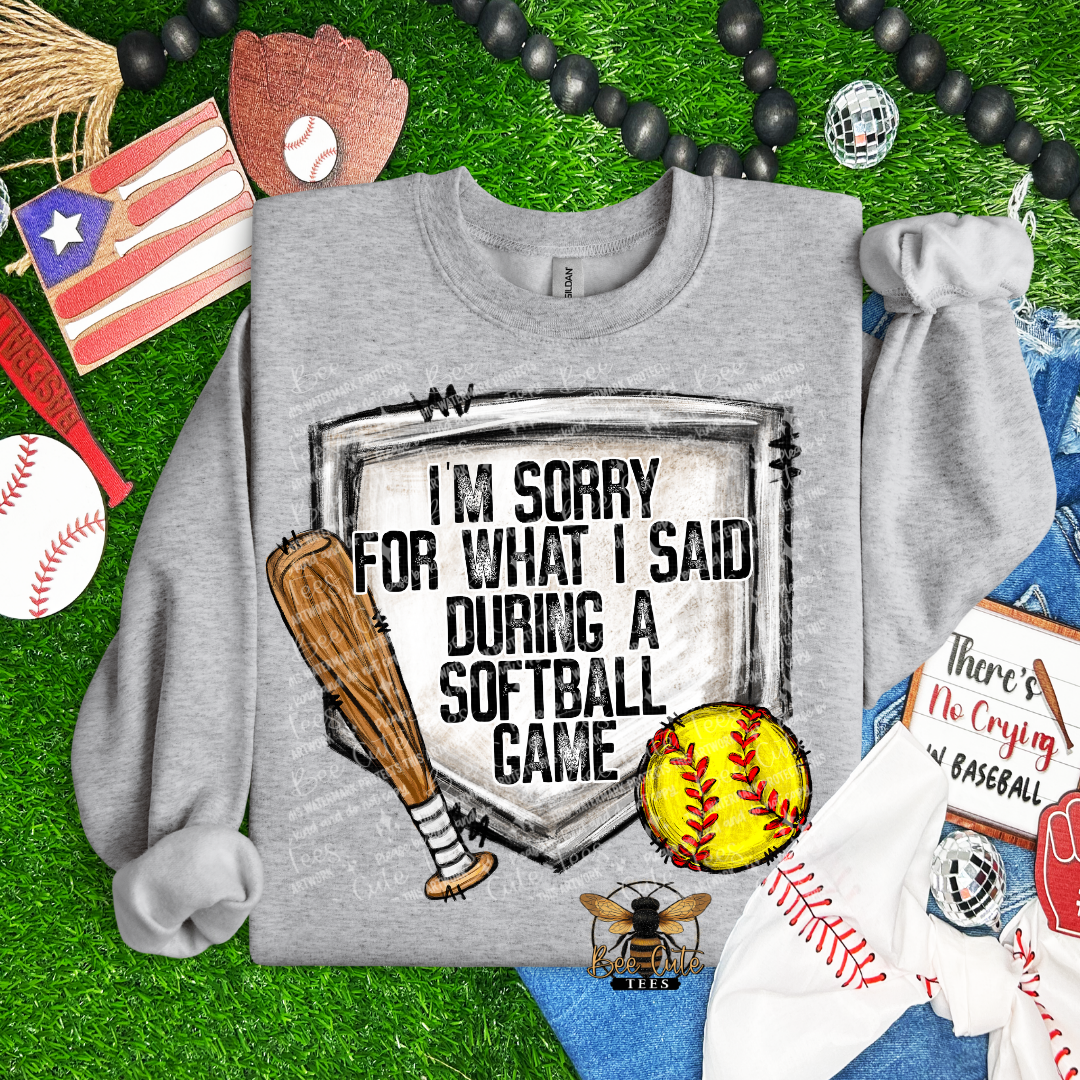 Gray sweatshirt with softball-themed design on grass with sports-themed accessories.