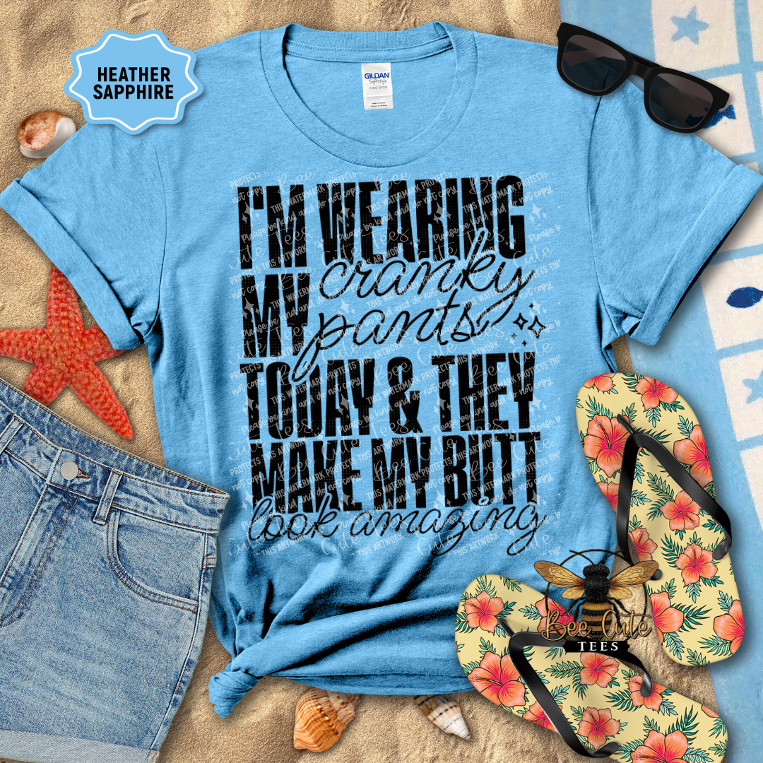 Blue t-shirt with humorous text, sunglasses, flip-flops, and denim shorts on a beach-themed background.
