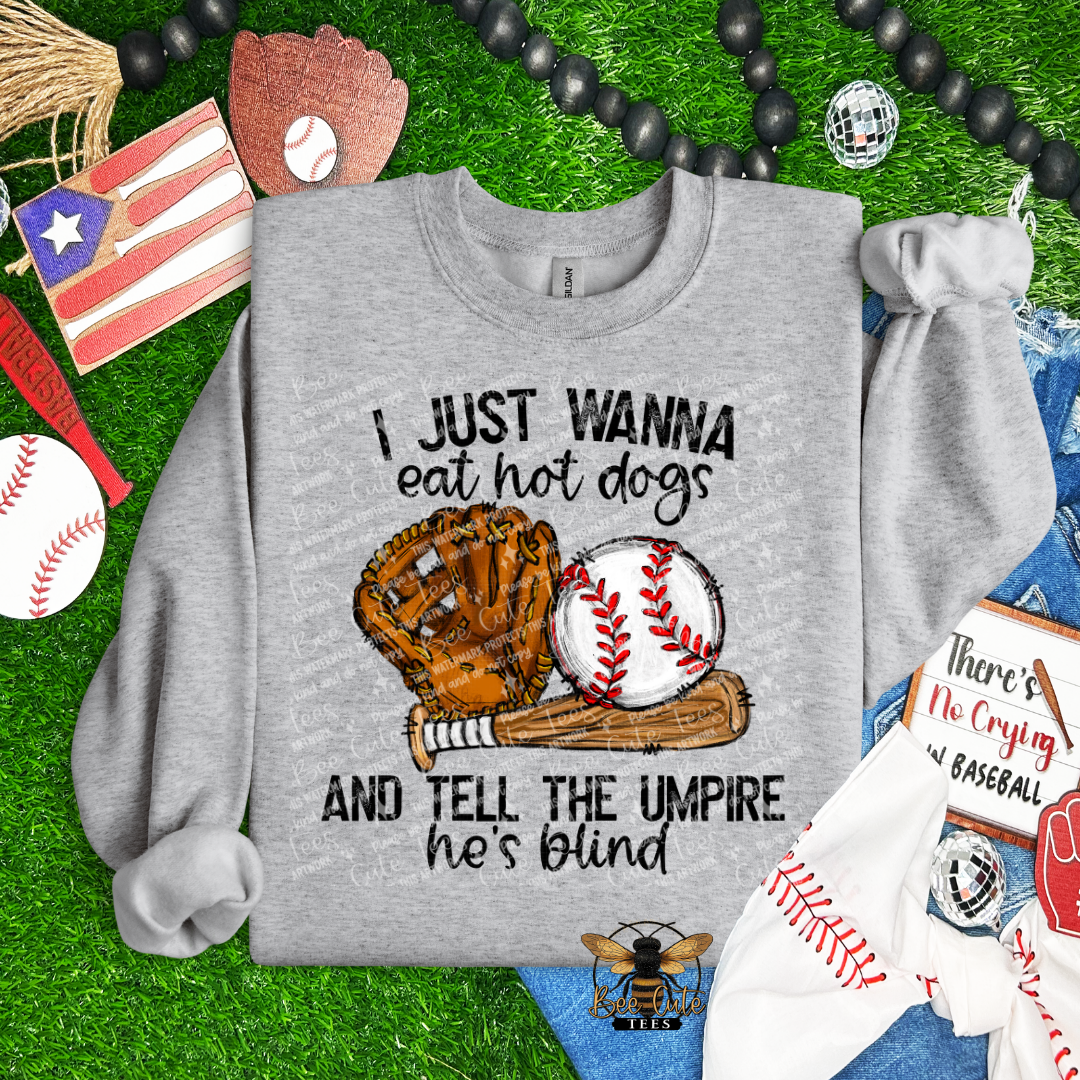 Gray sweatshirt with sports-themed design on grass with sports equipment.