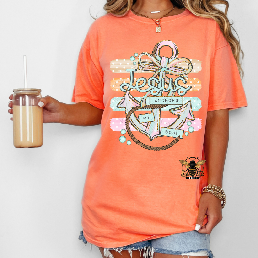 Person wearing an orange t-shirt with a graphic design holding a drink.