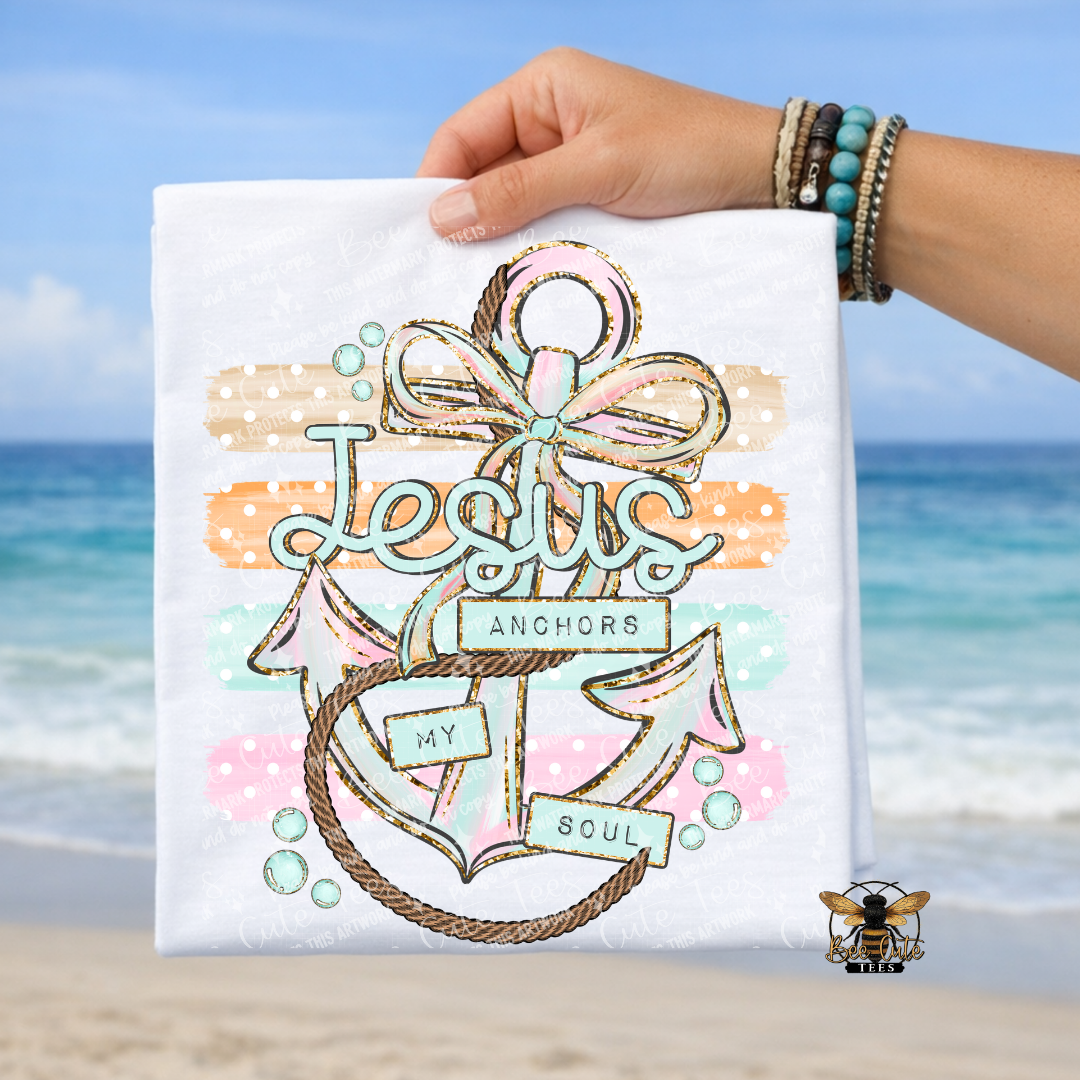 Hand holding a white t-shirt with an anchor design and 'Jesus Anchors My Soul' text on a beach background.