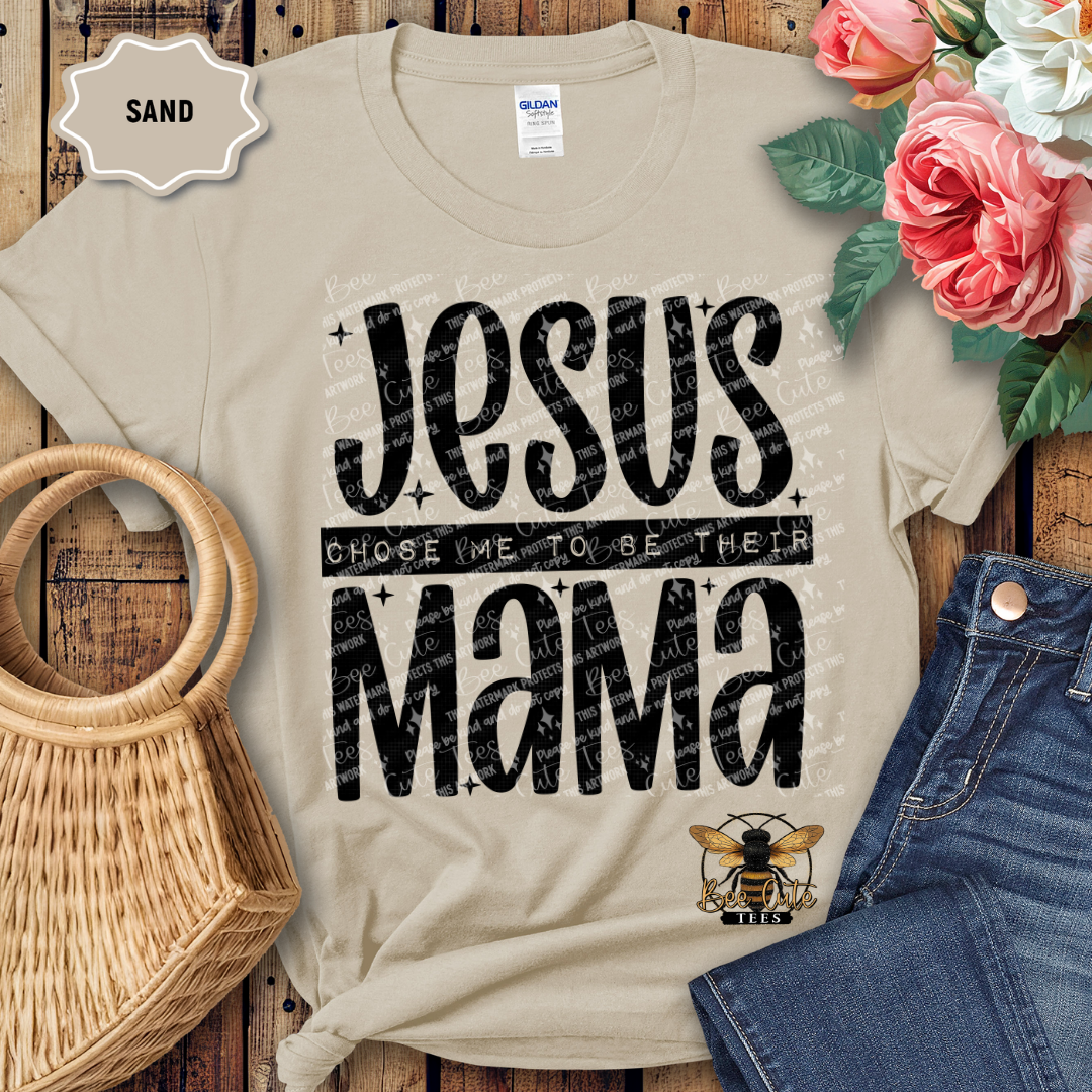 Beige t-shirt with 'Jesus Chose Me to be Their Mama' text, placed on a wooden surface with flowers and jeans.