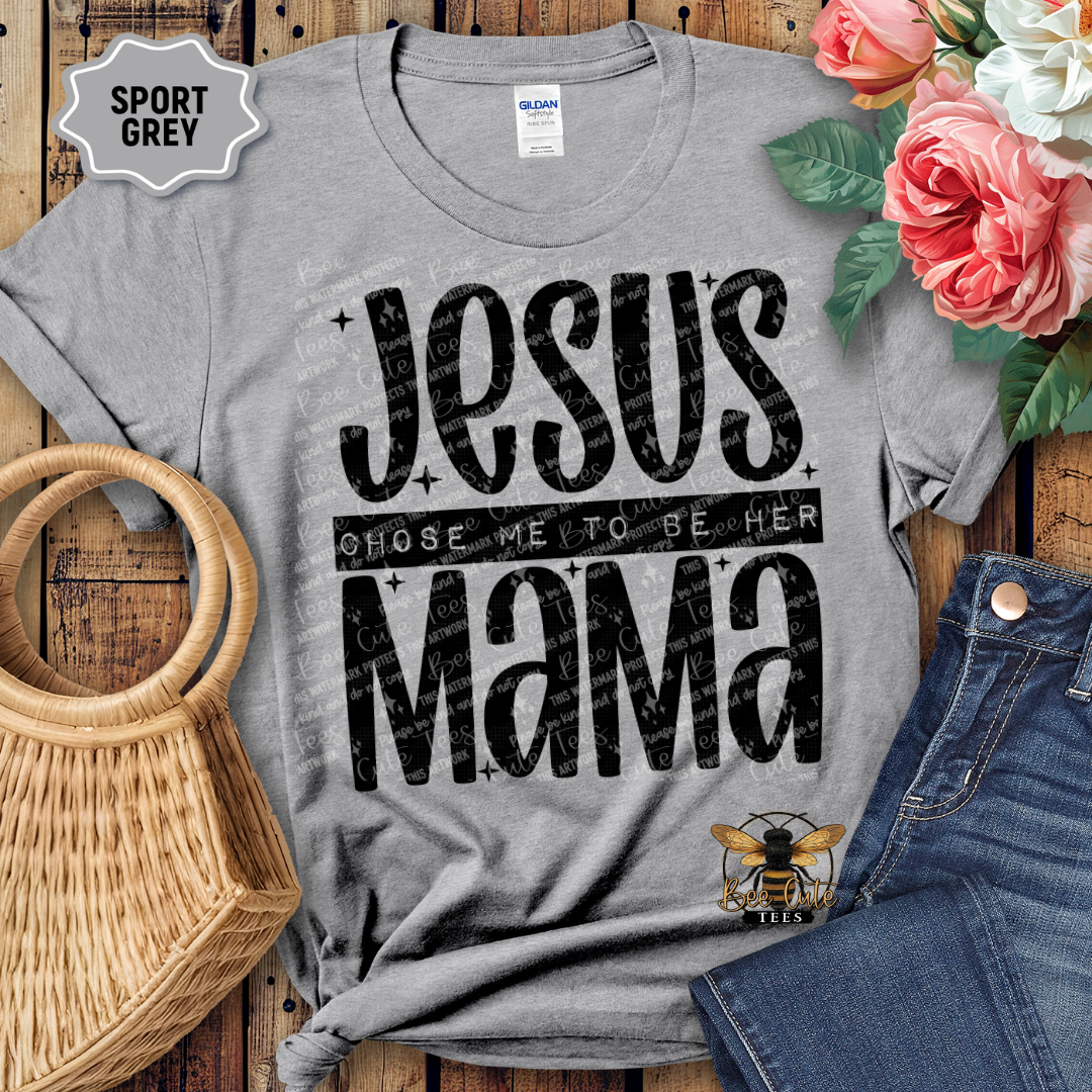 Gray t-shirt with 'Jesus chose me to be her mama' text on a wooden surface with flowers and jeans.