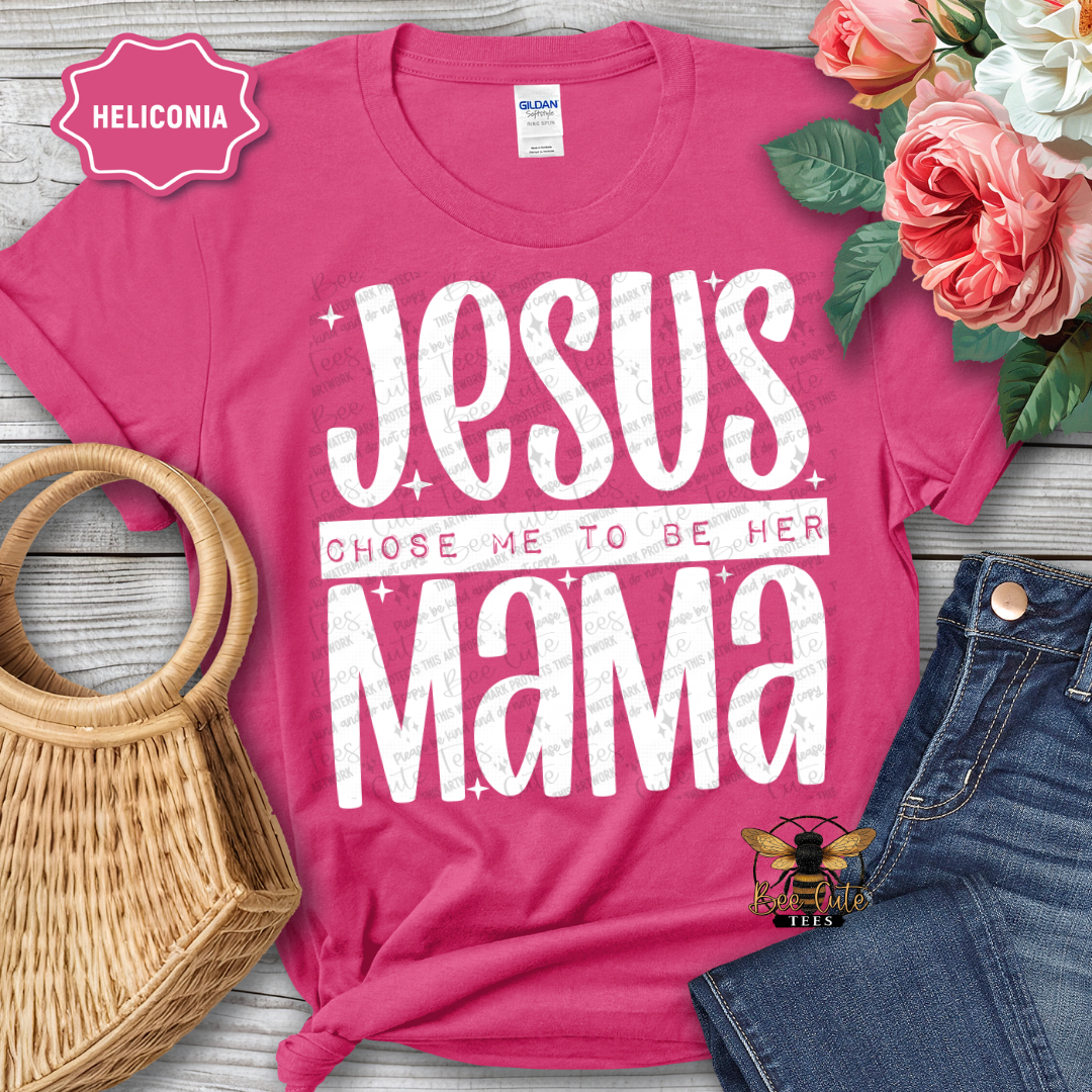 Pink t-shirt with 'Jesus chose me to be her mama' text, surrounded by flowers and denim jeans on a wooden surface.