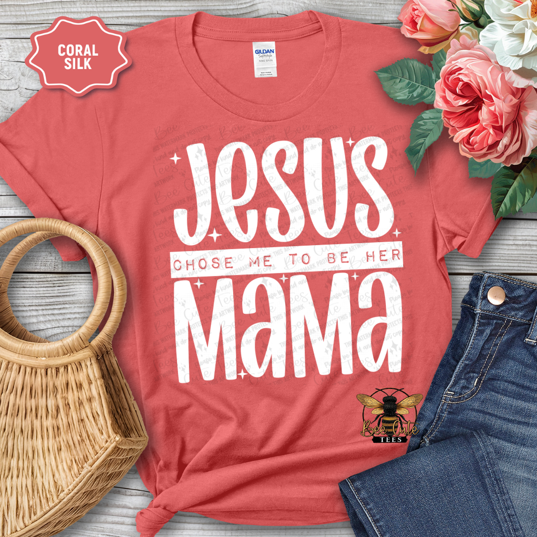 Red t-shirt with 'Jesus chose me to be her mama' text, surrounded by flowers and denim jeans on a wooden surface.