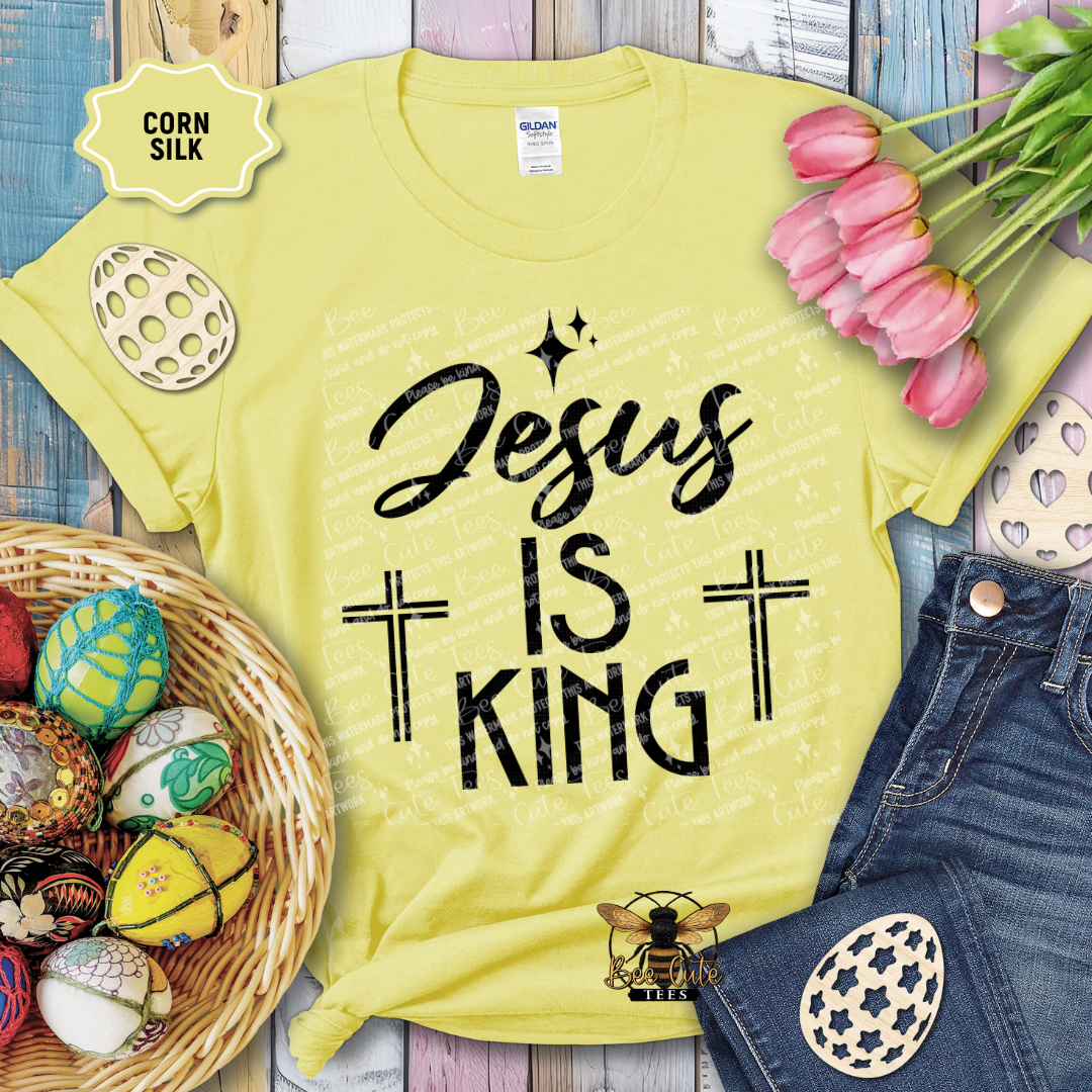 Yellow t-shirt with 'Jesus is King' text, surrounded by Easter decorations on a wooden surface.