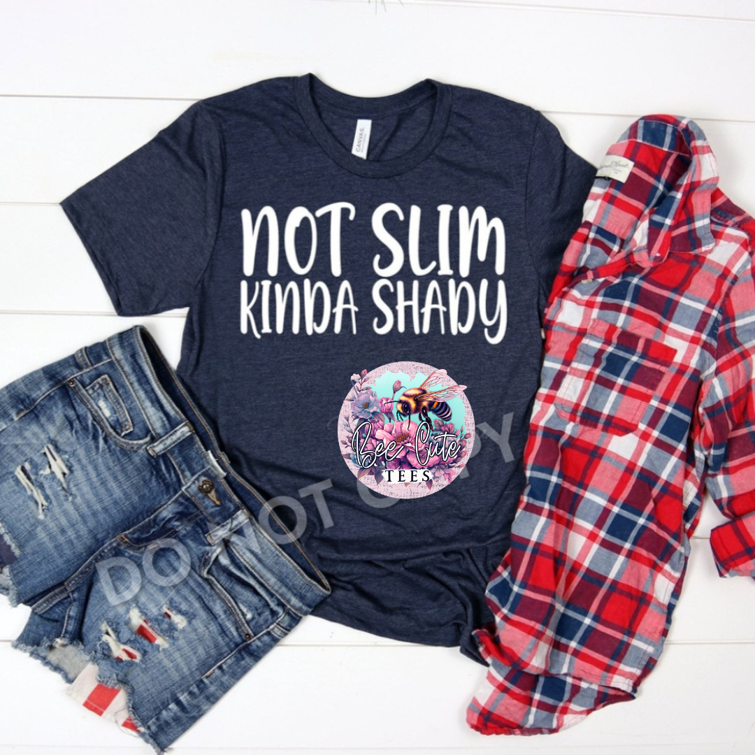 Navy t-shirt with 'Not Slim Kinda Shady' text, surrounded by denim shorts and a plaid shirt on a white background.