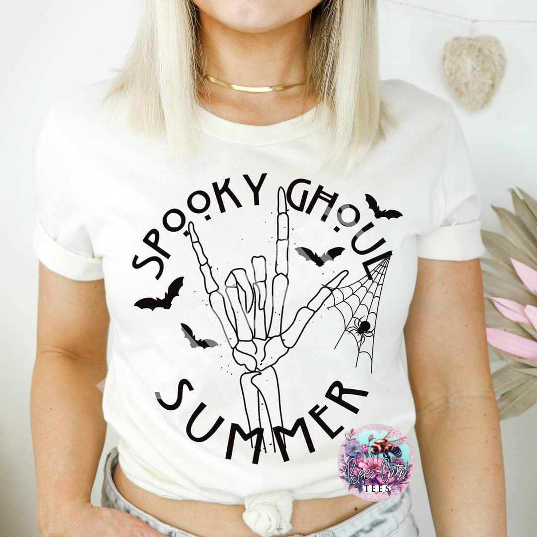 a woman wearing a white t-shirt with a black Halloween inspired design with a plant in the background