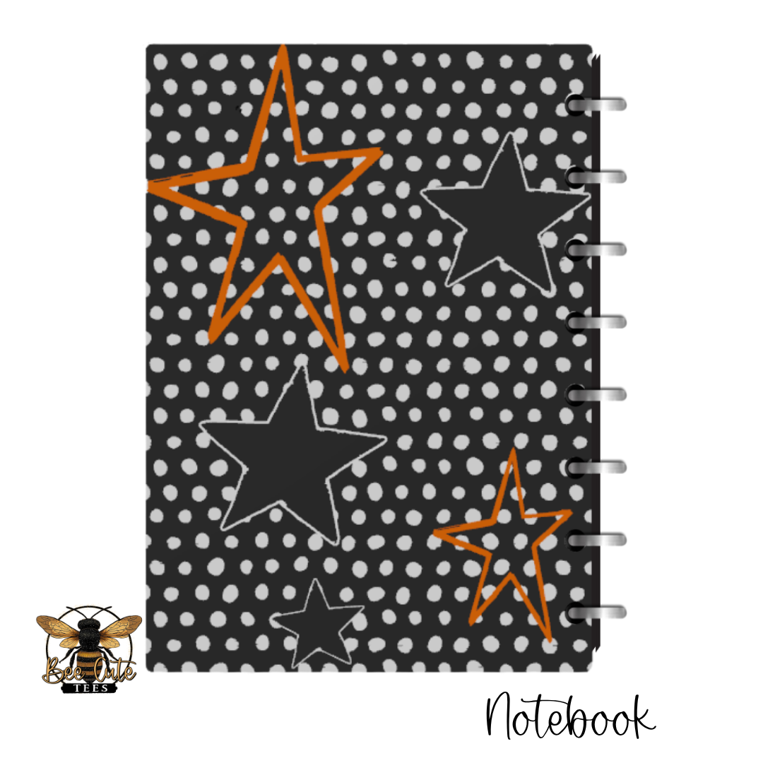 A spiral-bound notebook with a black cover decorated with white polka dots and large outlined stars in black and orange. The image is shown on a white background with a bee logo in the bottom-left corner and the word 'Notebook' in the bottom-right.