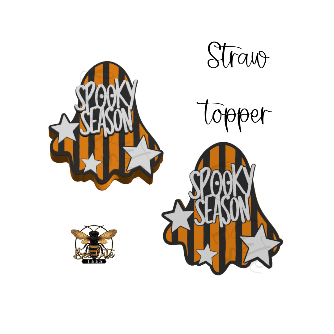 Two Halloween-themed ghost-shaped straw toppers on a white background, one with orange and black stripes and silver stars reading 'SPOOKY SEASON,' and another with a bee logo. Handwritten text says 'Straw topper.