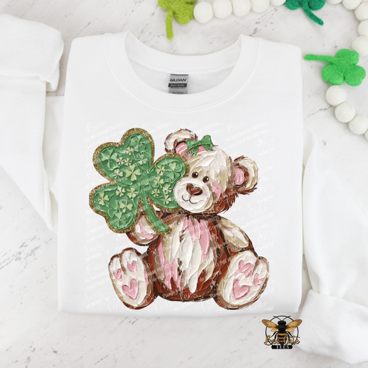 White sweatshirt with a teddy bear and clover design on a light gray background