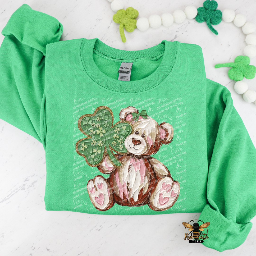 Green sweatshirt with teddy bear and clover design on a white background