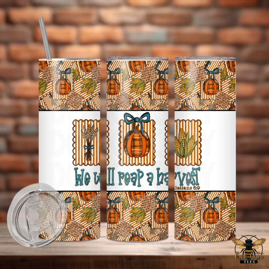 Three views of a 20 oz skinny tumbler with a clear lid and straw, featuring a fall harvest pattern with pumpkins, corn, wheat, and the text 'We will reap a harvest' on a white band. The tumbler is shown against a brick wall background with a wooden table surface.