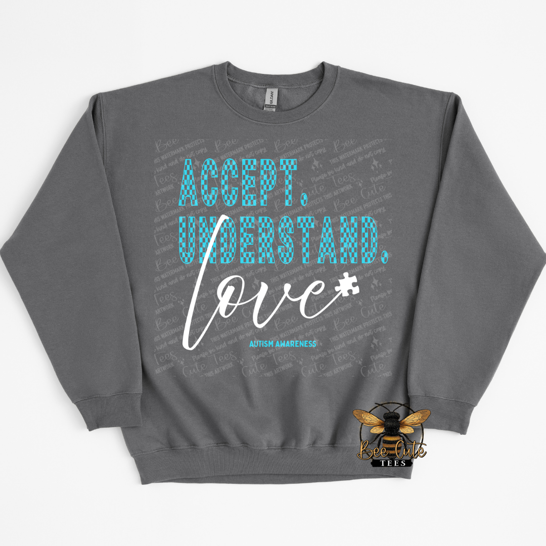 Gray sweatshirt with 'Accept. Understand. Love.' text and puzzle piece graphic on a white background