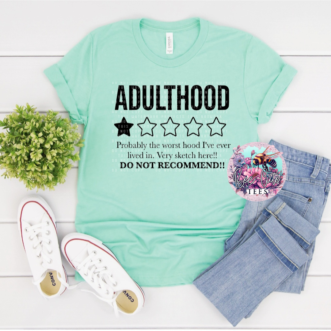 Mint green t-shirt with humorous text, paired with jeans and sneakers on a light wooden surface.