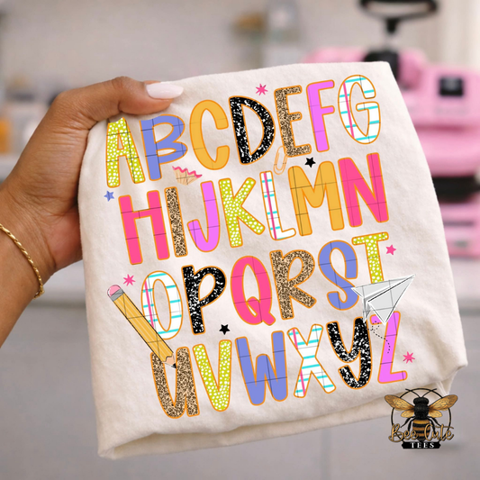 White t-shirt with colorful letters held by a hand, with a blurred background