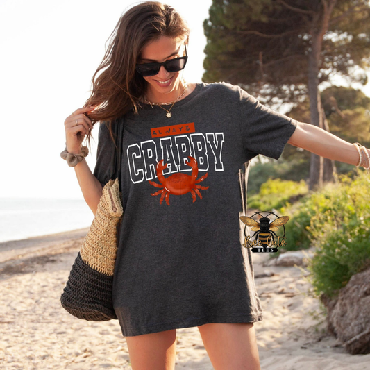 Woman wearing a 'Always Crabby' t-shirt with a crab graphic on a beach.