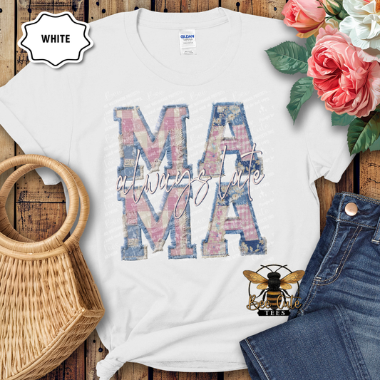 White t-shirt with 'MAMA' print on a wooden surface with flowers and denim jeans.