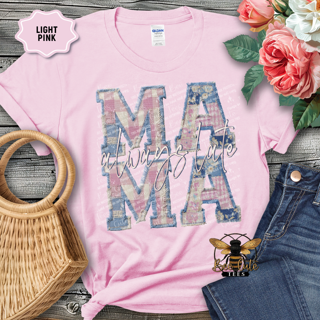 Light pink t-shirt with 'MAMA' design, surrounded by flowers and denim jeans on a wooden surface.