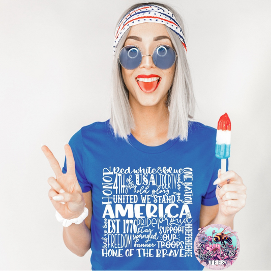 Smiling woman wearing a blue graphic t-shirt with a patriotic “America” word collage design, styled with round sunglasses and a red, white, and blue headband while holding a red-white-blue popsicle and making a peace sign.
