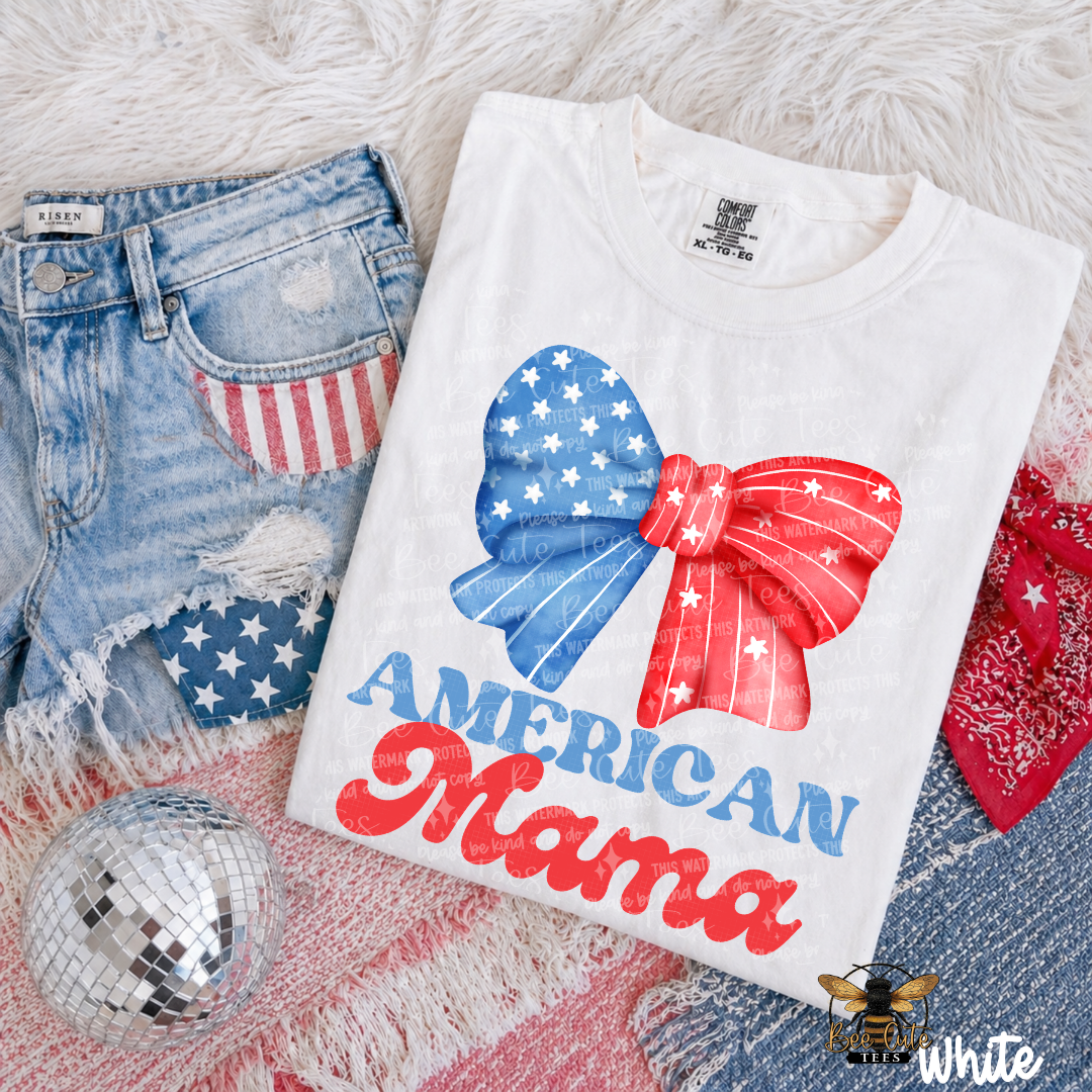 White t-shirt with 'American Mama' design on a textured surface with denim shorts and disco ball.