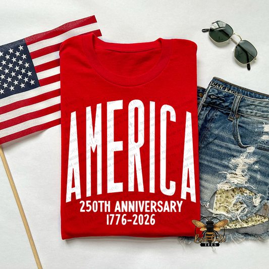 Red t-shirt with 'AMERICA 250TH ANNIVERSARY 1776-2026' text, American flag, sunglasses, and jeans on a white background.