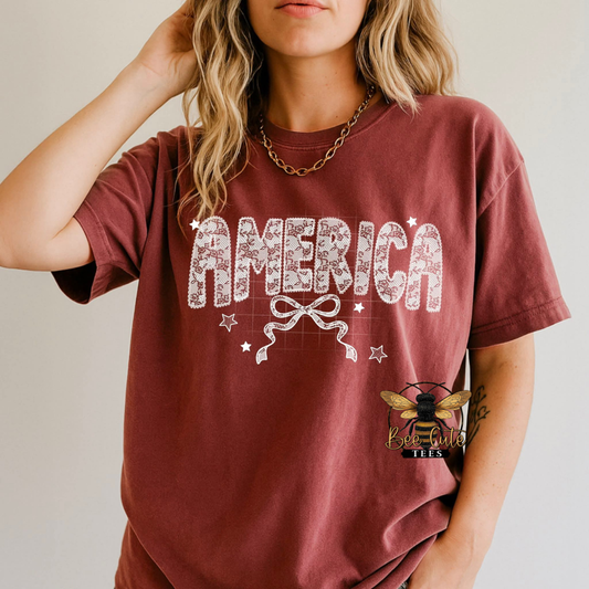 Person wearing a maroon t-shirt with 'AMERICA' design and a bee logo.