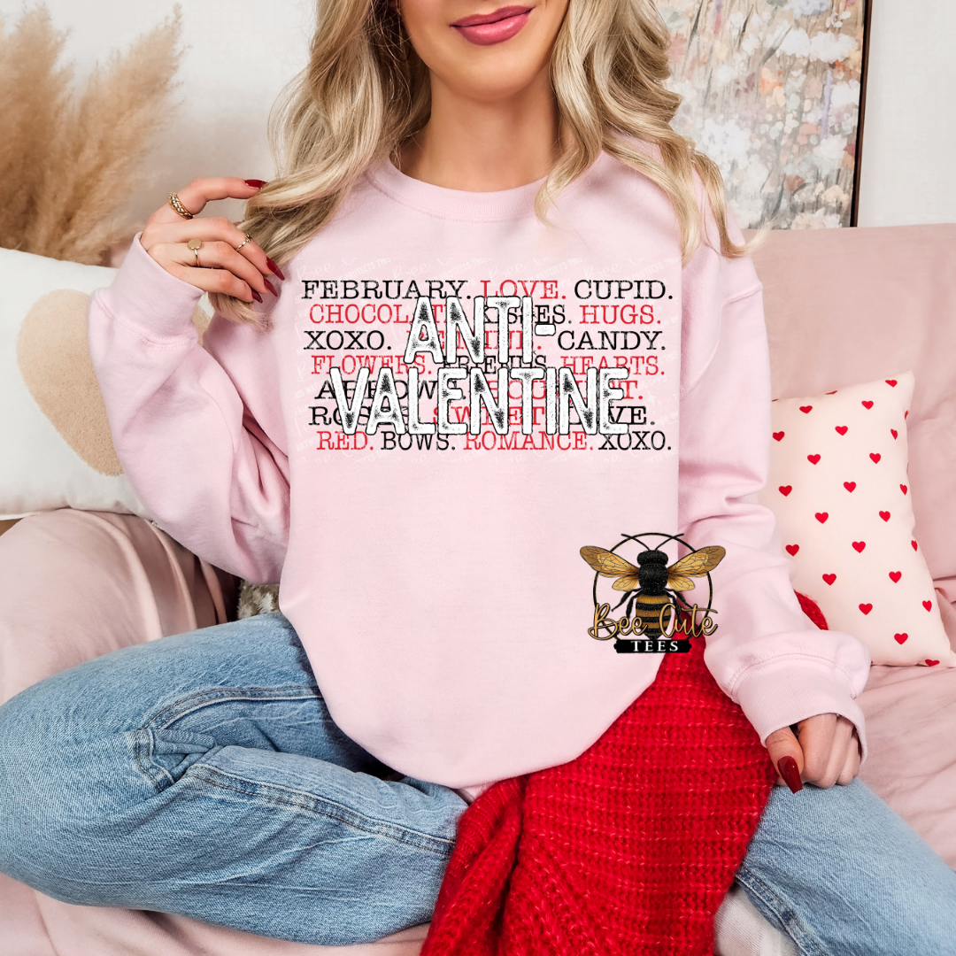 Person wearing a pink sweatshirt with Valentine's Day text design, sitting on a couch.