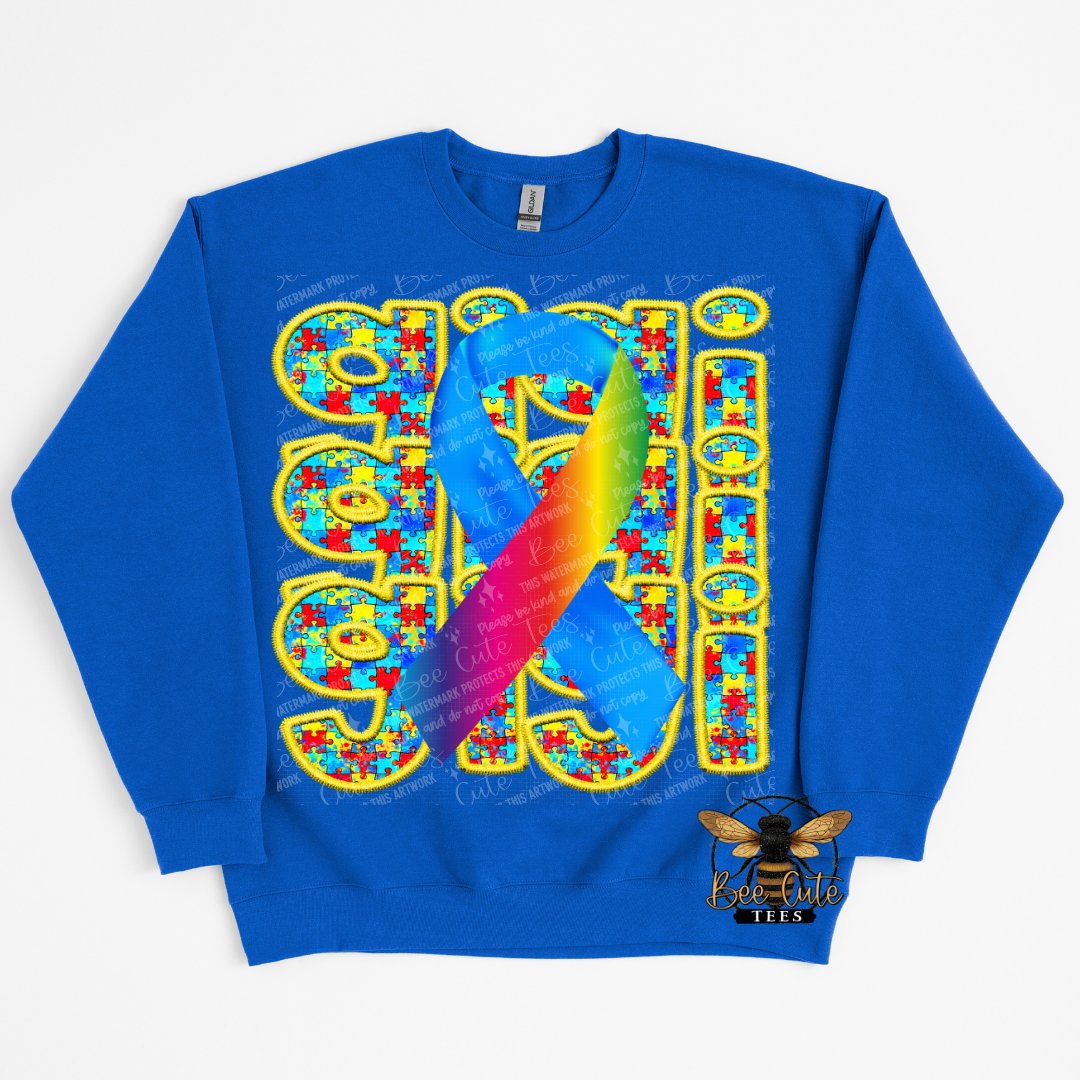 Blue sweatshirt with colorful design featuring a rainbow ribbon and puzzle pieces on a white background.