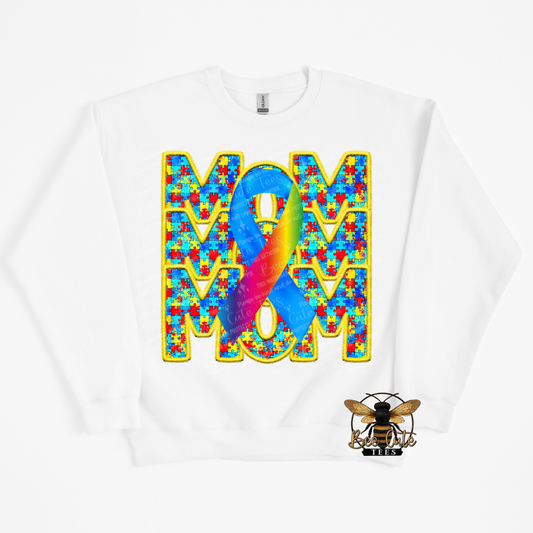 White sweatshirt with colorful 'MOM' design featuring a blue ribbon on a white background.