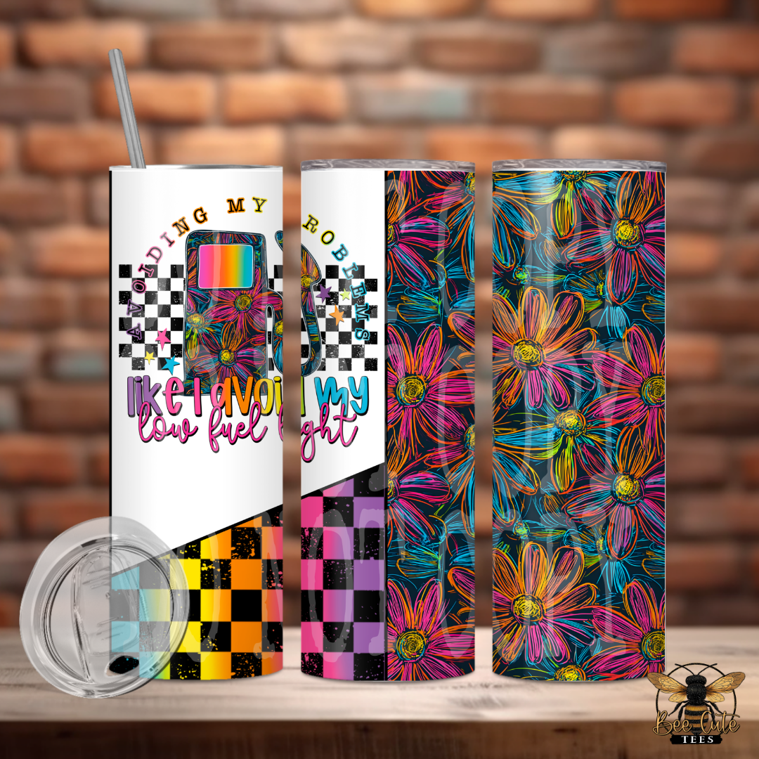 Three colorful tumblers with floral and abstract designs on a wooden surface with a brick wall background.