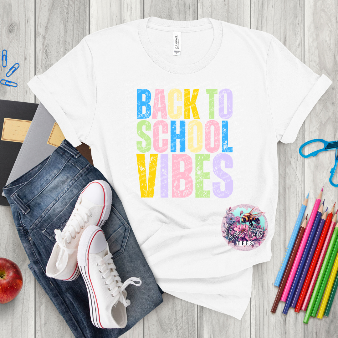 White t-shirt with 'Back to School Vibes' text, jeans, sneakers, and school supplies on a wooden surface