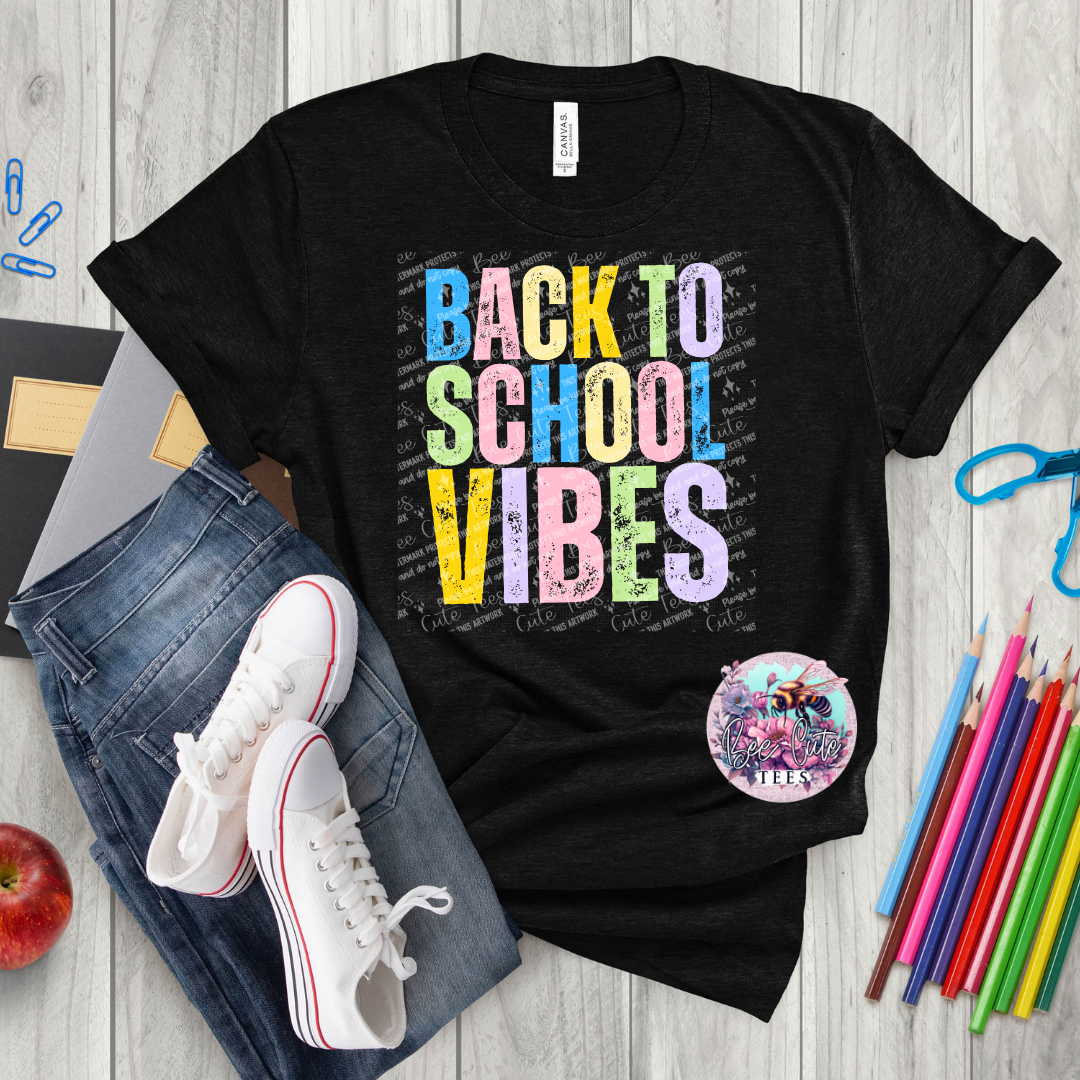 Black t-shirt with 'Back to School Vibes' text on a wooden surface with jeans, sneakers, and stationery items.