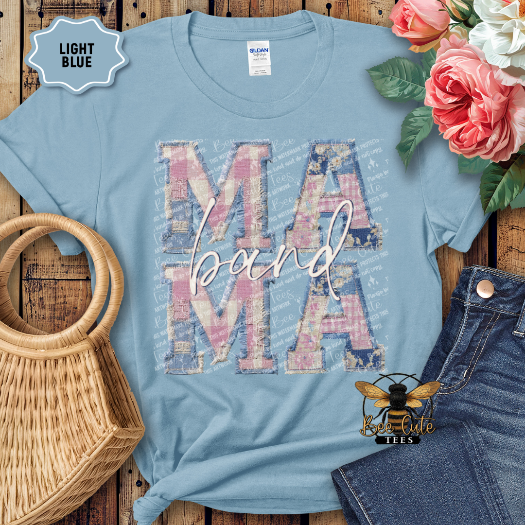 Light blue t-shirt with 'MAMA' design on a wooden surface with flowers and jeans.