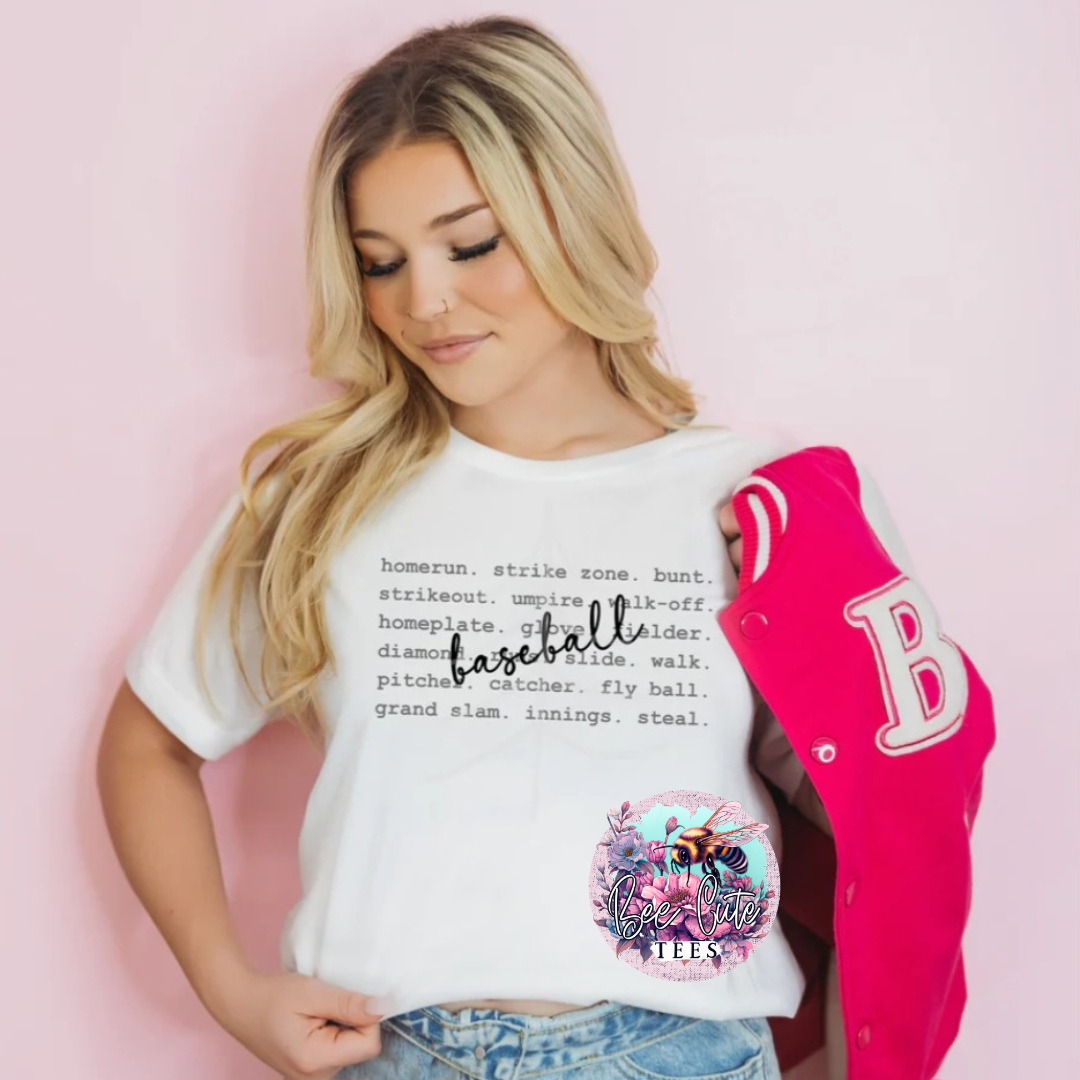 Woman wearing a white t-shirt with baseball terms and a pink letterman jacket on a pink background