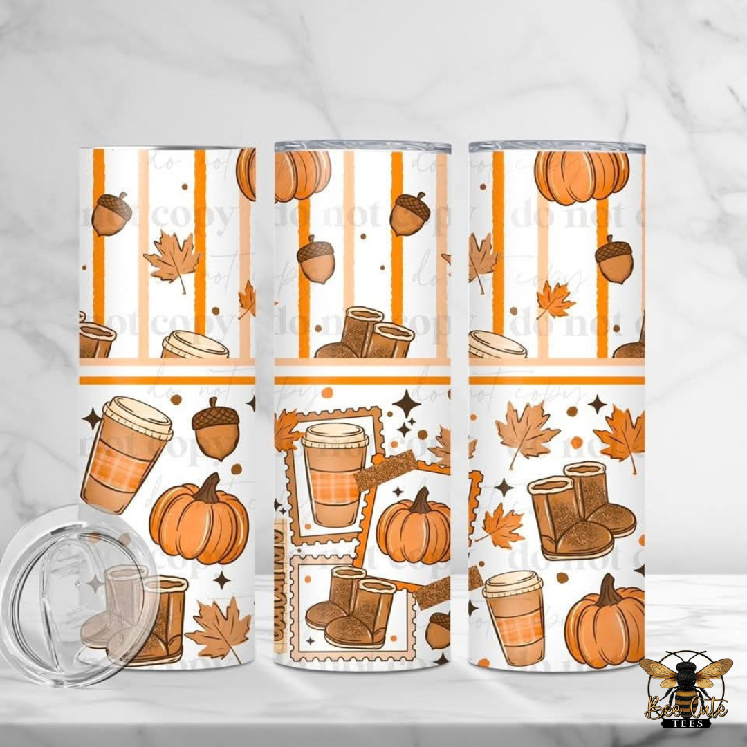Three tall insulated tumblers with a white background and an autumn coffee-themed print featuring pumpkins, acorns, maple leaves, boots, and takeaway coffee cups. A clear lid is shown lying on the left.