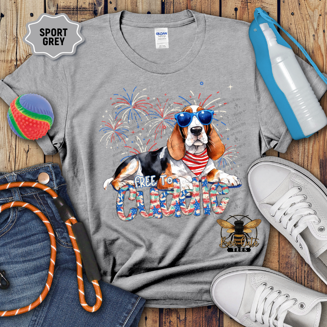 Gray t-shirt with a dog graphic and 'Free to Cuddle' text on a wooden surface with accessories.