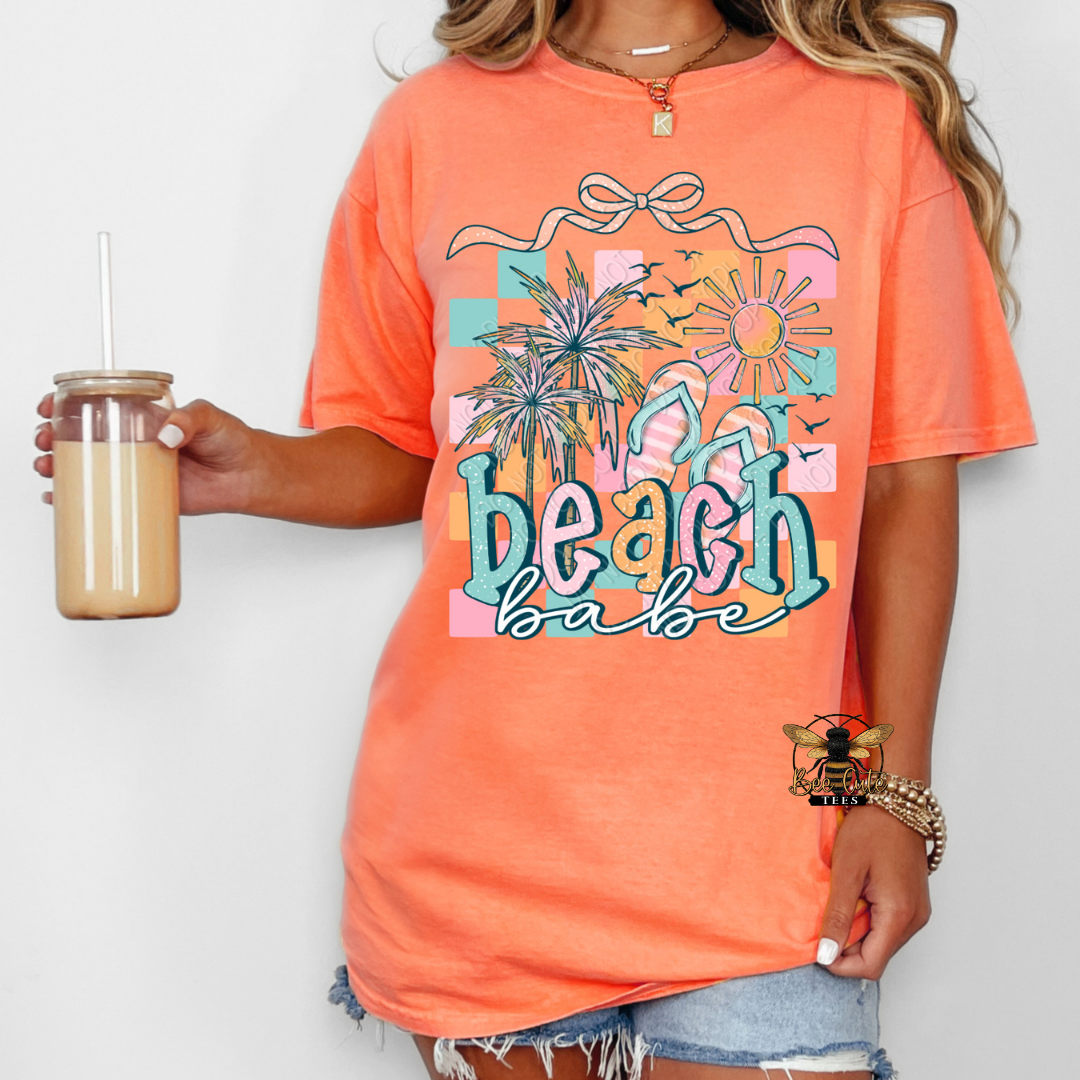 Person wearing an orange 'Beach Babe' t-shirt holding a drink.
