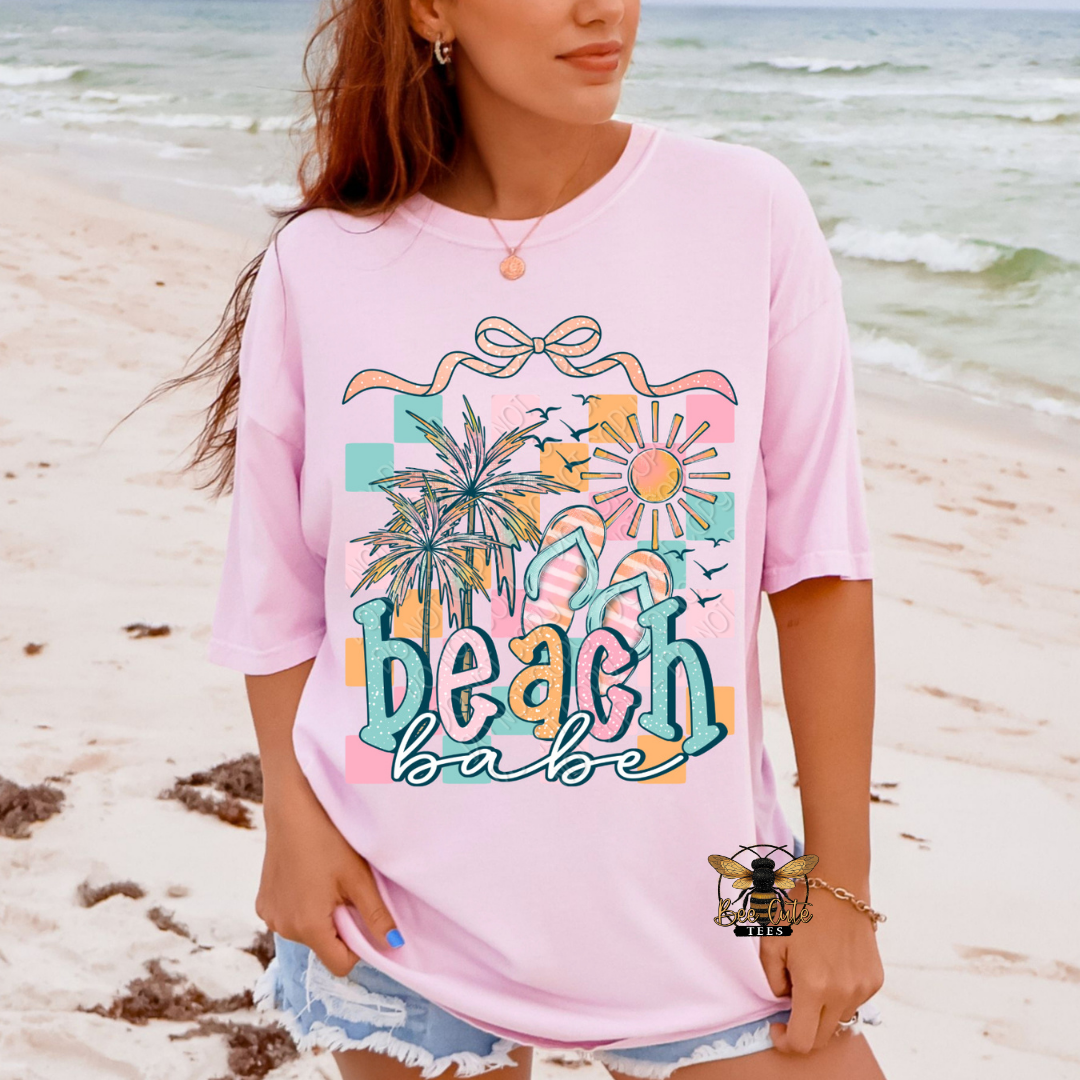 Person wearing a pink 'beach babe' shirt on a beach