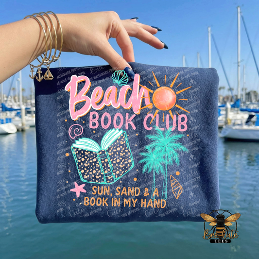Hand holding a pouch with 'Beach Book Club' design against a marina background
