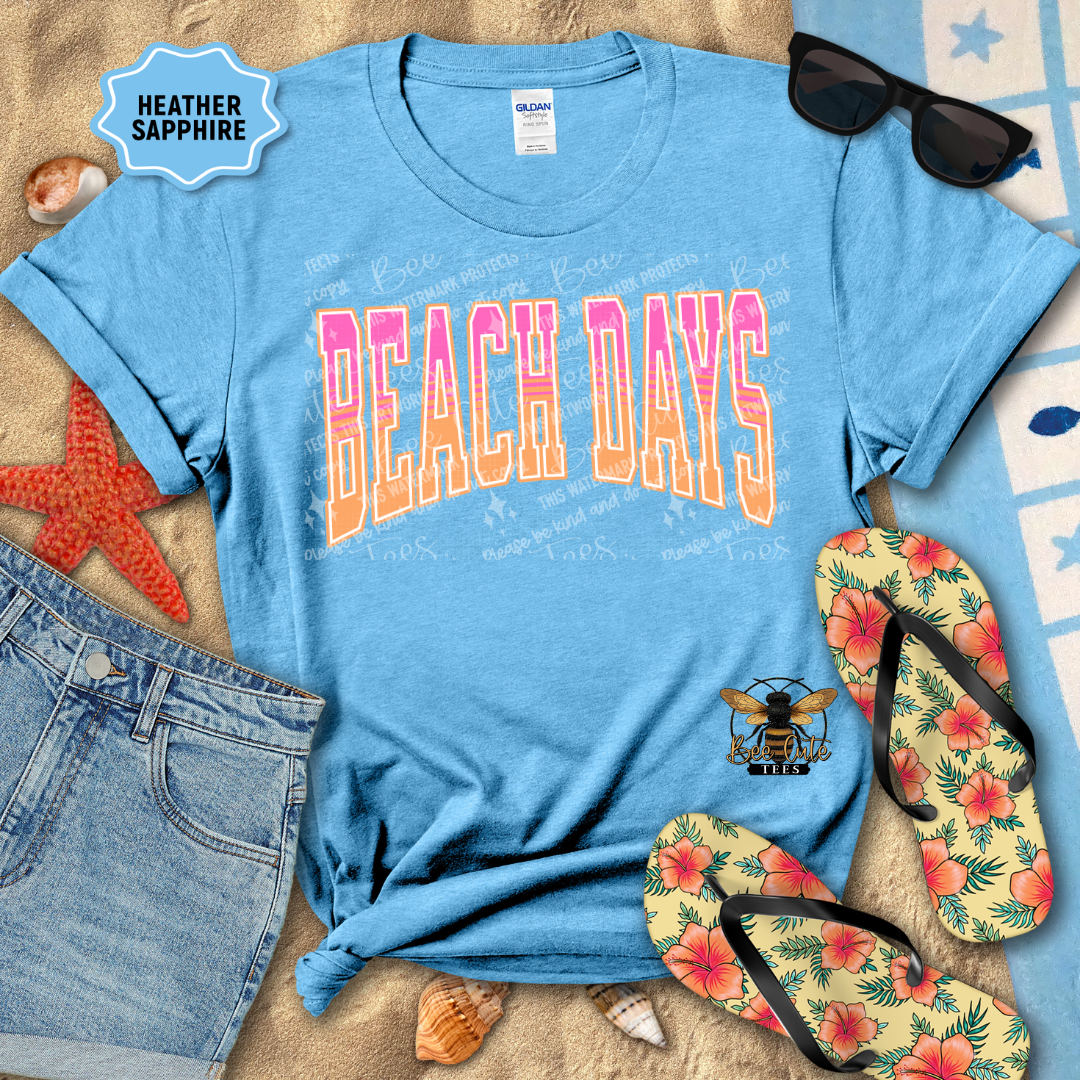 Blue t-shirt with 'Beach Days' text, sunglasses, flip-flops, and beach accessories on sand.