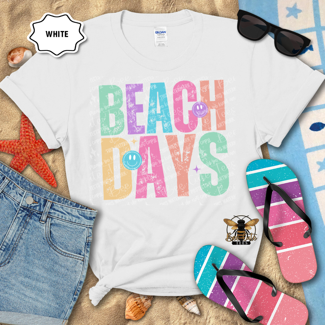 White t-shirt with 'Beach Days' text, sunglasses, flip-flops, and denim shorts on a sandy background.