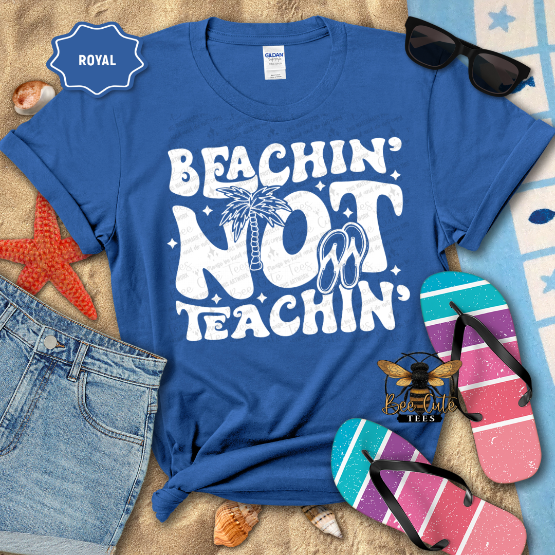 Blue t-shirt with 'Beachin' Not Teachin' design, sunglasses, and flip-flops on a beach-themed background.