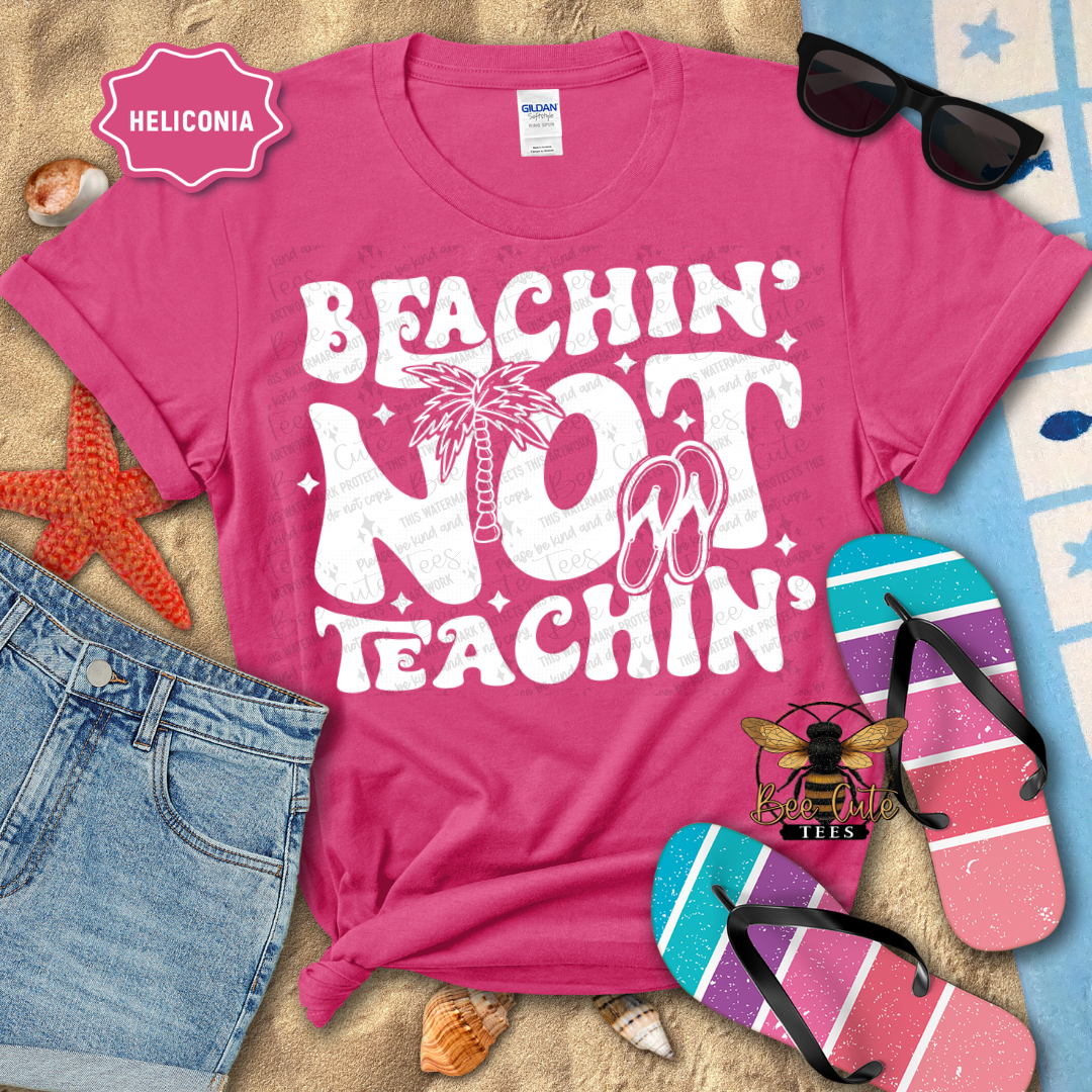 Pink t-shirt with 'Beachin' Not Teachin' design on a beach-themed background with sunglasses and flip-flops.